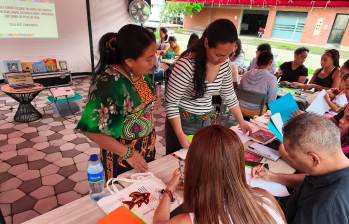 En compañía de Mileidy Cuéllar, indígena guna, Carmen Blanco revisa el trabajo de los asistentes al taller sobre molas. FOTO CORTESÍA