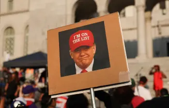 Una persona sostiene una fotografía del presidente Donald Trump con un sombrero rojo que dice “Estoy en la lista” frente al Ayuntamiento de Los Ángeles. FOTO: AFP. 