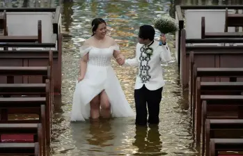 La pareja caminando en el agua en la iglesia donde se casaron. FOTO: Tomada de redes sociales
