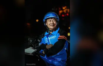 El repartidor chino Wang Jibing, de 56 años, sostiene un ejemplar de su libro de poemas mientras trabaja. En julio de 2026 ganó el Premio Literario Lu Xun, uno de los más importantes de China. / Foto: BaiduWiki 