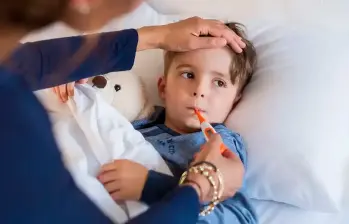 Niño enfermo, recostado en una cama, bajo el cuidado de un adulto, una imagen para graficar la función de la Ley Isaac. FOTO: Getty