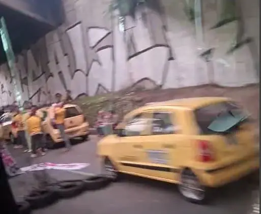 Los taxistas bloquean con sus vehículos y con llantas la vía, dando paso intermitente a un solo carril. FOTO: TOMADA DE VIDEO
