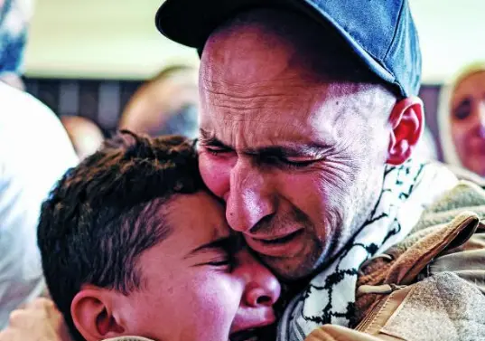 Un preso palestino, liberado tras intercambio de presos y rehenes y el acuerdo de alto el fuego entre Israel y Hamás, abraza a un niño a su llegada en autobús a Ramalla. FOTO AFP