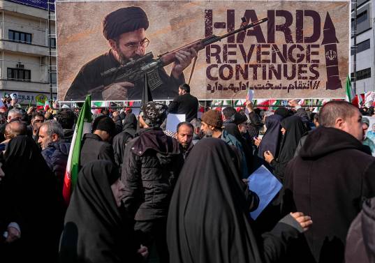 Una pancarta que representa al ayatolá Mojtaba Jamenei, el nuevo Líder Supremo de Irán e hijo del fallecido líder ayatolá Alí Jamenei, es exhibida mientras se le muestra empuñando un arma en la plaza Enghelab (Revolución) en Teherán, el 11 de marzo de 2026, mientras los asistentes se reúnen para los funerales de comandantes del Cuerpo de la Guardia Revolucionaria Islámica (CGRI), el ejército y otros fallecidos en los primeros días de los ataques de Estados Unidos e Israel contra Irán. El Líder Supremo de Irán, el ayatolá Alí Jamenei, murió en los ataques del 28 de febrero, y desde entonces el conflicto ha escalado en ataques de represalia por toda la región. (Foto de Khoshiran / Middle East Images vía AFP)