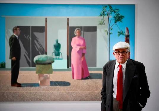 David Hockney murió a los 88 años. Aquí con una de sus pinturas <i>Fred y Marcia Weisman</i>, expuesta en París. FOTO AFP