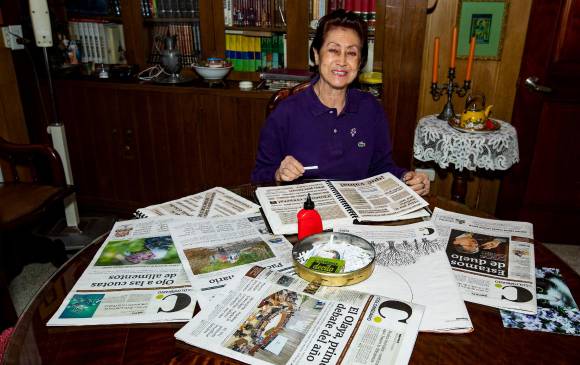 Inés Vélez Muñoz en su comedor, espacio que usa para recortar y pegar los recortes de periódico en sus bitácoras, generalmente mientras mira la televisión.