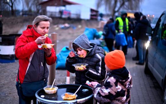 Familia de refugiados se alimenta en Medyka, Polonia, tras cruzar la frontera desde Ucrania. FOTO GETTY