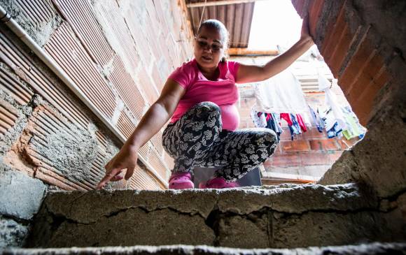 Nélida Tapasco señala una de las grietas que se abren paso por los muros, escaleras y pisos de su casa en el barrio Santa Inés, en donde vive desde hace 17 años. FOTO Julio César Herrera