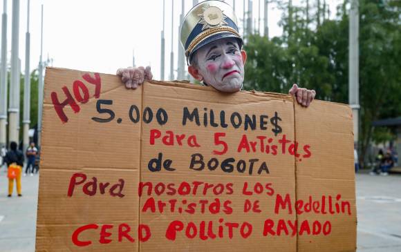 El clown Álvarez mientras sostiene un trozo de cartón con un mensaje que critica el dinero gastado por EPM en el concierto de apertura del Alumbrado. Foto: Manuel Saldarriaga Quintero.
