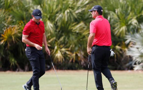 Rory McIlroy de Irlanda del Norte (izq.), y Patrick Reed, de EE. UU., dos de varios jugadores que lucieron una camiseta roja y pantalones negros en homenaje a Tiger Woods. EFE