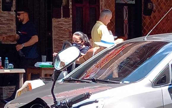 La mujer de sombrero le entrega propaganda política al hombre del carro. FOTO EL COLOMBIANO
