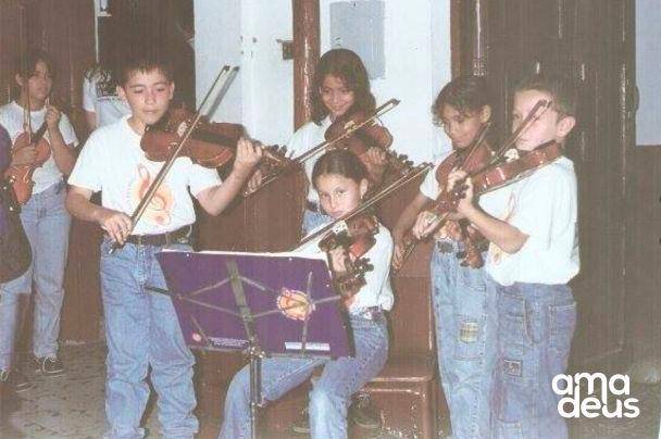 La que está sentada en la silla es Ana López, quien aprendió a tocar violín en la Red y hoy en día hace parte de la Orquesta Filarmónica de Medellín. Cortesía.