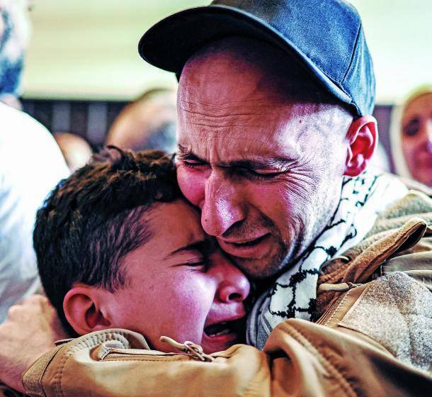 Un preso palestino, liberado tras intercambio de presos y rehenes y el acuerdo de alto el fuego entre Israel y Hamás, abraza a un niño a su llegada en autobús a Ramalla. FOTO AFP