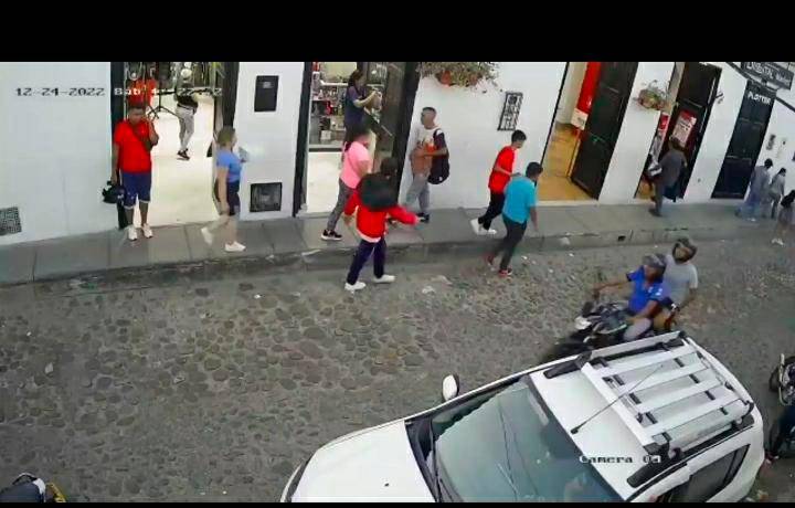 El hombre de camiseta roja con el casco en la mano fue asesinado tras recibir tres puñaladas. FOTO: TOMADA DEL VIDEO