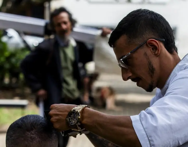 Marlon Uribe, motilando a uno de sus clientes en el Parque Bolívar. FOTO Julio Herrera. 