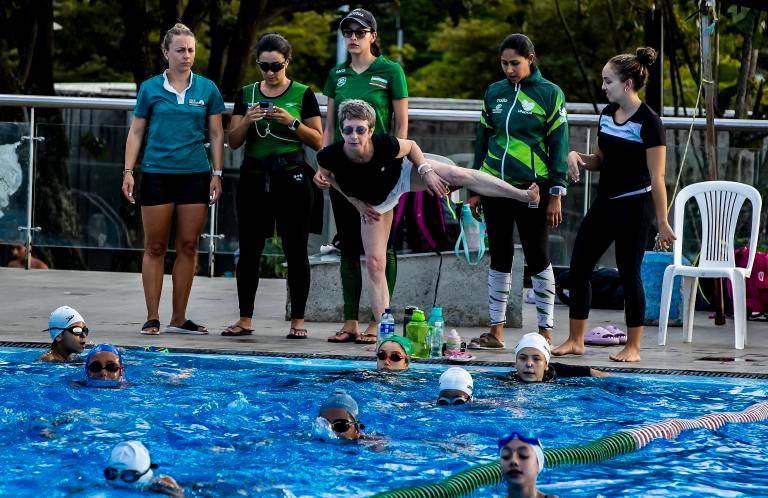 Julia (blusa negra y pantaloneta) realizando la explicación de la técnica fuera del agua, para que los deportistas la ejecuten en la piscina, mientras las entrenadoras toman nota de cada detalle. FOTO jaime pérez 