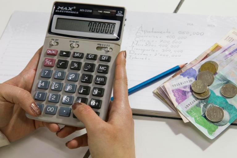 Persona con calculadora en mano haciendo la cuenta de cuánto le deberán pagar por su recargos dominicales. FOTO: EL COLOMBIANO