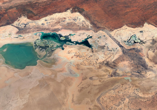Vista aérea del paisaje desértico en Australia Occidental, capturada por Google Earth, donde contrastan las lagunas turquesa con las formaciones rocosas y los tonos ocres del terreno. FOTO cortesía Google Earth