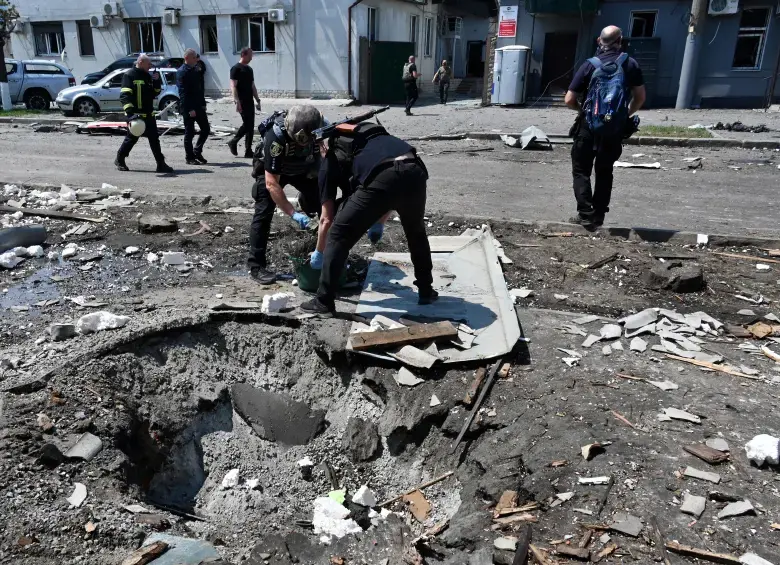 Agentes policiales ucranianos trabajan junto a un cráter tras un ataque con aviones no tripulados. FOTO: AFP