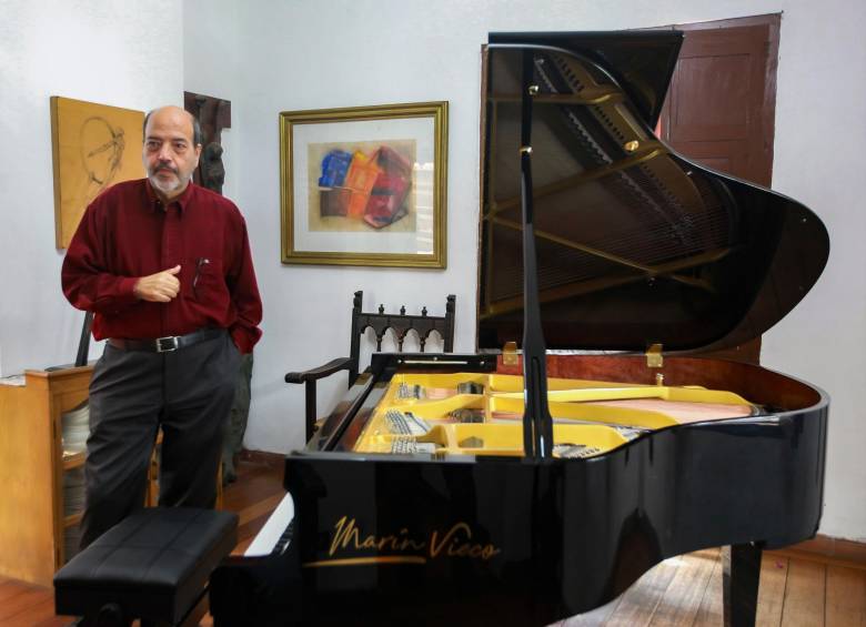 Jorge Alberto Marín junto al primer piano de la marca Marín Vieco. FOTO Manuel Saldarriaga