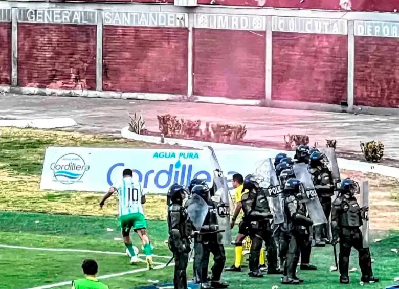 Este es uno de los cobros de tiro de esquina en los que Edwin Cardona es cuidado por un grupo de policías para protegerlo de los objetos que le lanzaban desde las tribua. FOTO CORTESÍA NACIONAL 