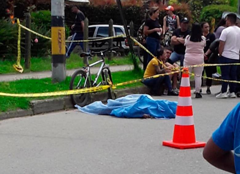 Personas que se encontraban en la zona cubrieron el cuerpo del ciclista fallecido mientras las autoridades hacían la inspección correspondiente. FOTO: CORTESÍA