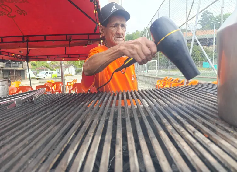 Desde muy temprano, Óscar empieza labores. A veces atizando el carbón, ubicando las mesas y las sillas y limpiando para recibir a los comensales. FOTO Julio César Herrera.