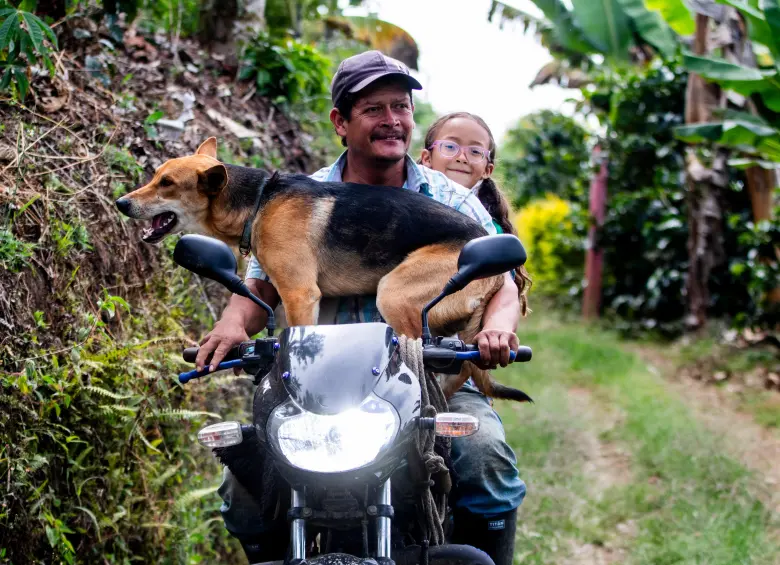 Rodolfo Tobón trabajaba del jornal cuando un día una patrona le ofreció un lote a buen precio en La Soledad, lo compró y le sembró 4.700 árboles de café. Lleva a su hija y su mascota en la moto. FOTO JULIO CÉSAR HERRERA