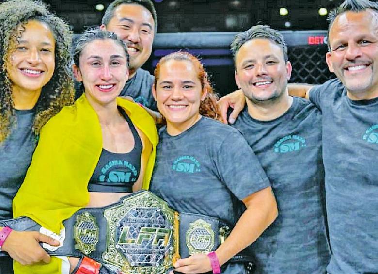 La antioqueña Sabina Mazo con su equipo de trabajo y el cinturón que la acredita como la campeona mundial. FOTO CORTESÍA