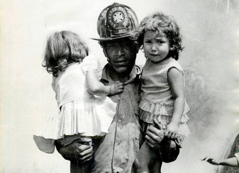 Un bombero de Medellín carga a dos niñas desorientadas en medio de la evacuación de 15 familias que vivían cerca a la estación Santiago durante el primer día del incendio. FOTO: Hervásquez