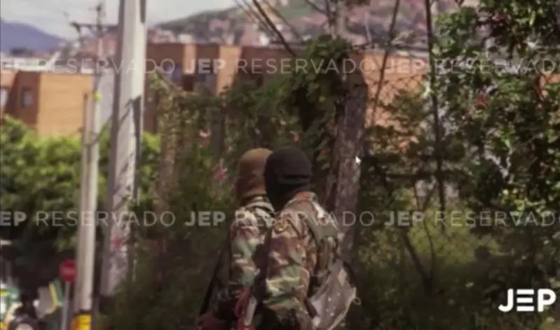 La foto que expuso la JEP durante la audiencia, muestra a dos hombres con camuflado militar, capuchas y fusiles terciados. FOTO: CORTESÍA JEP.