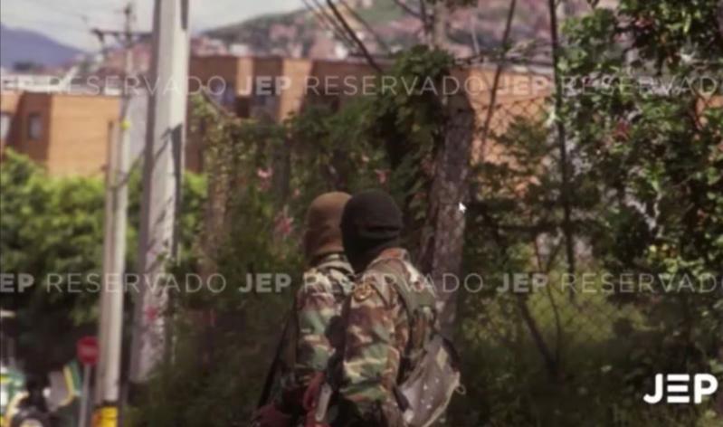 La foto que expuso la JEP durante la audiencia, muestra a dos hombres con camuflado militar, capuchas y fusiles terciados. FOTO: CORTESÍA JEP.