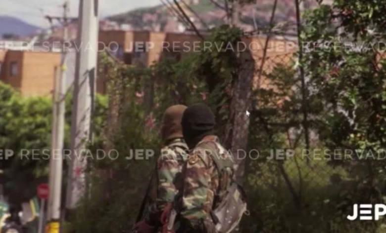 La foto que expuso la JEP durante la audiencia, muestra a dos hombres con camuflado militar, capuchas y fusiles terciados. FOTO: CORTESÍA JEP.