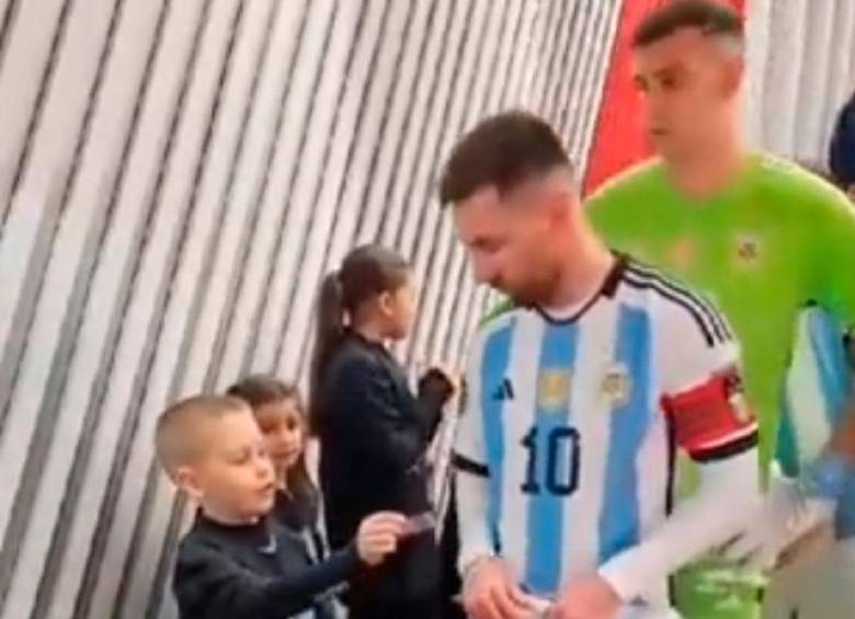 Este es el momento en el que el niño sacó de su bolsillo dos stickers y se los regala a Messi. FOTO CAPTURA DE PANTALLA