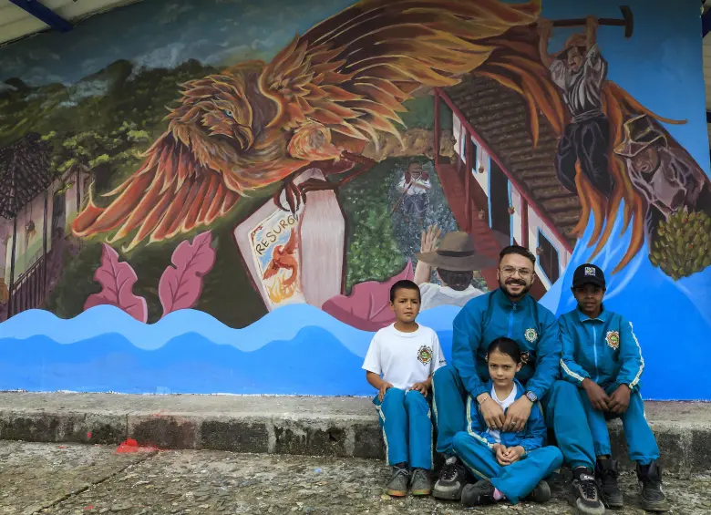 El profesor Esneyder Gutiérrez junto a los únicos alumnos que hay en la escuela veredal. Atrás, un graffiti con un ave Fénix que representa el resurgir de La Linda Foto: Andrés Camilo Suárez Echeverry