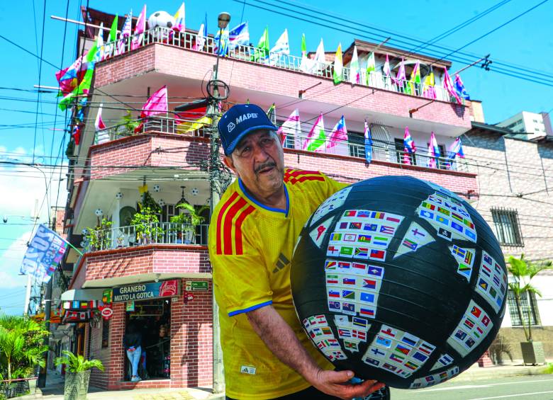 Don Gustavo posando con el ‘balón mundialista’, decorado con más de 300 banderas de las selecciones que han participado a lo largo de la historia en las copas mundiales de fútbol. FOTO Manuel Saldarriaga. 