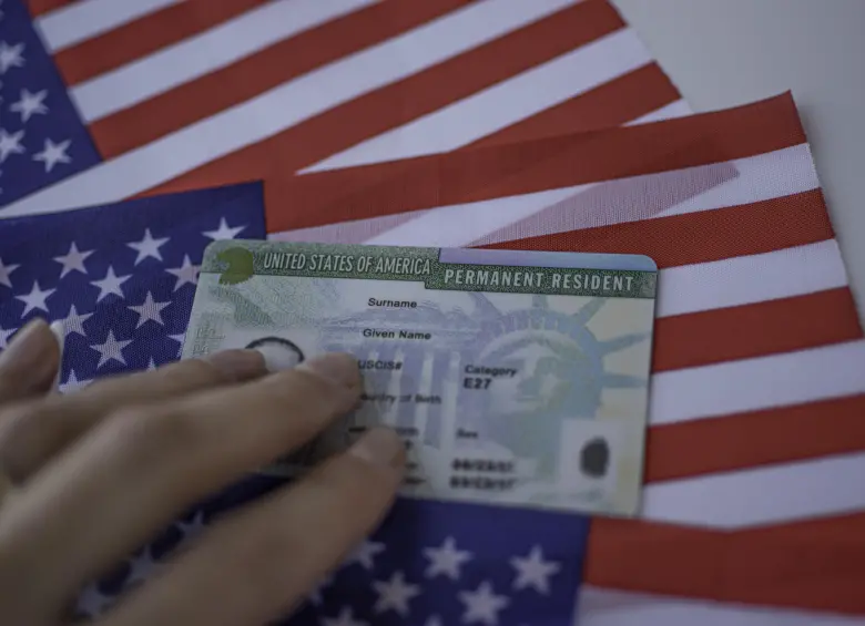 Permanent Resident Green card of United states of America on flag of USA. Above close up view.