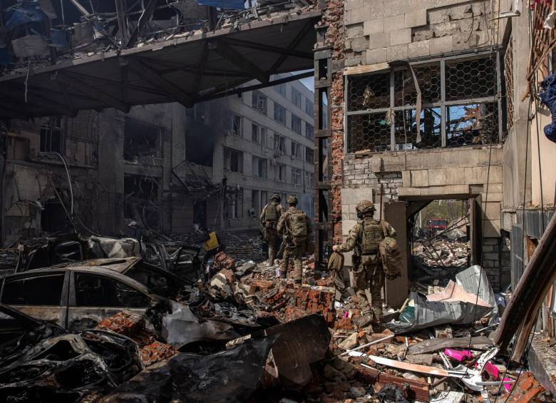 Soldados ucranianos caminan al lado de una estructura dañada por un bombardeo ruso en Kharkiv. FOTO: EFE.