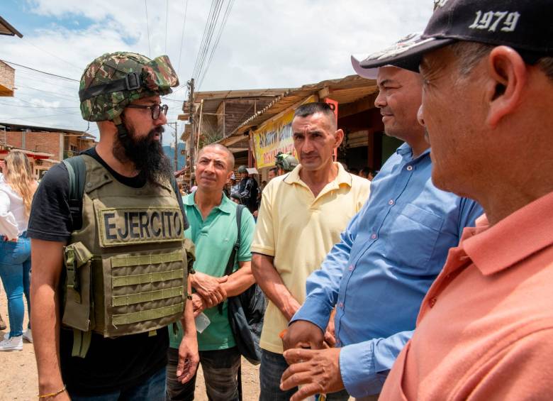 El director de la UNGRD, Carlos Carrillo, otrora ha sido duro crítico del Ejército, con chaleco y casco del Ejército mientras habla con habitantes del corregimiento. FOTO Presidencia