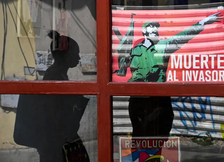 Una mujer pasa junto a un cartel del difunto líder cubano Fidel Castro. Foto Afp