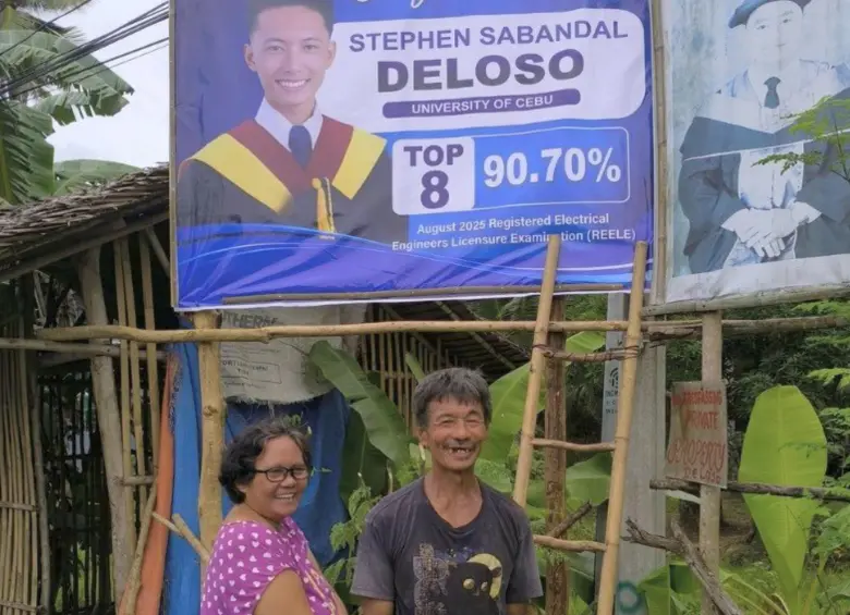 Los padres felices al frente del cartel de su hijo. FOTO: Tomada de redes sociales