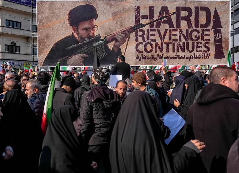 Una pancarta que representa al ayatolá Mojtaba Jamenei, el nuevo Líder Supremo de Irán e hijo del fallecido líder ayatolá Alí Jamenei, es exhibida mientras se le muestra empuñando un arma en la plaza Enghelab (Revolución) en Teherán, el 11 de marzo de 2026, mientras los asistentes se reúnen para los funerales de comandantes del Cuerpo de la Guardia Revolucionaria Islámica (CGRI), el ejército y otros fallecidos en los primeros días de los ataques de Estados Unidos e Israel contra Irán. El Líder Supremo de Irán, el ayatolá Alí Jamenei, murió en los ataques del 28 de febrero, y desde entonces el conflicto ha escalado en ataques de represalia por toda la región. (Foto de Khoshiran / Middle East Images vía AFP)