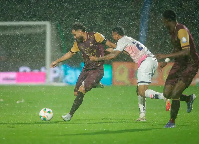 Juan Pablo Nieto protege en balón en un campo difícil por la lluvia en Bogotá. FOTO COLPRENSA