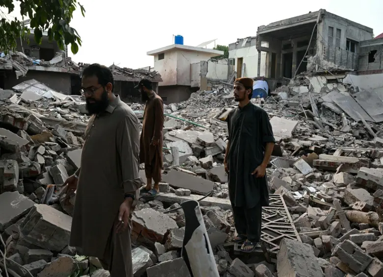 Residentes locales permanecen sobre los escombros de las estructuras destruidas en Pakistán. Foto: AFP