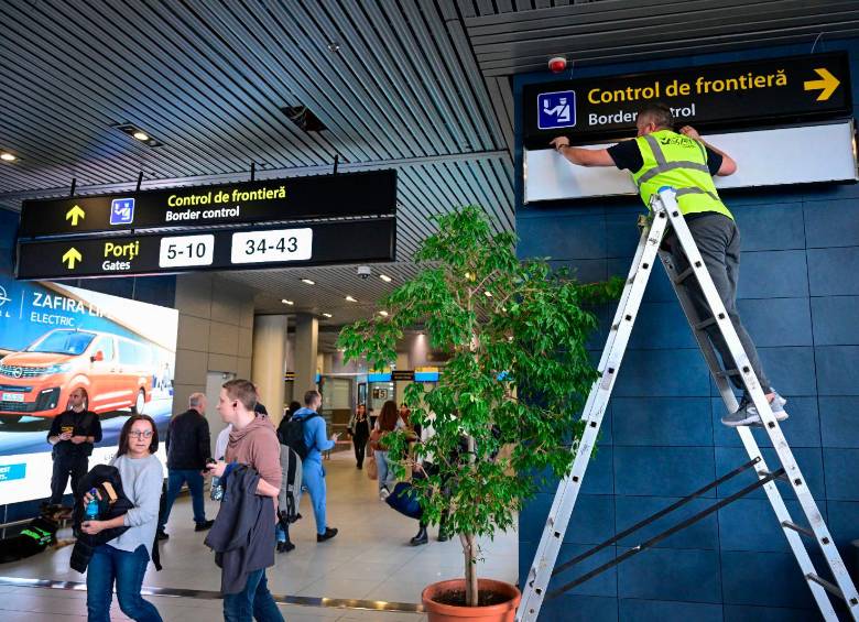 Un trabajador del aeropuerto de internacional de Bucarest Henri Coanda, en Rumania, modifica la señalización tras el ingreso del país a la zona Schengen. FOTO: AFP
