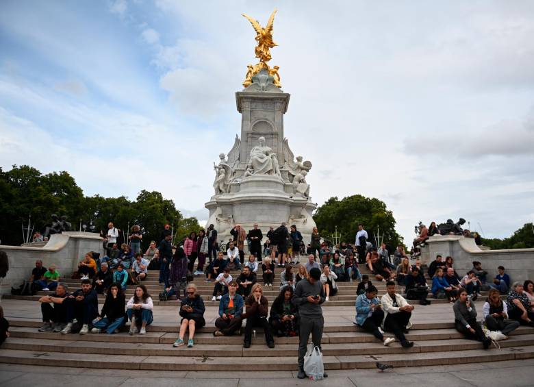 Británicos y turistas esperan noticias en los escalones del Queen Victoria Memorial frente al Palacio. FOTO: EFE