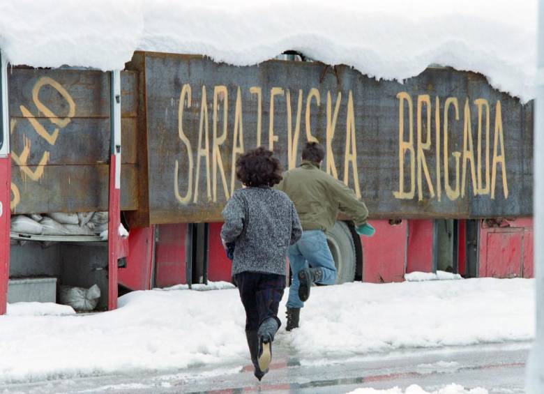 Una pareja corre para ponerse a salvo de los francotiradores detrás de un bus con la leyenda <i>“Sarajevo brigade”</i>, el 28 de marzo de 1993, durante el asedio a Sarajevo FOTO: AFP.