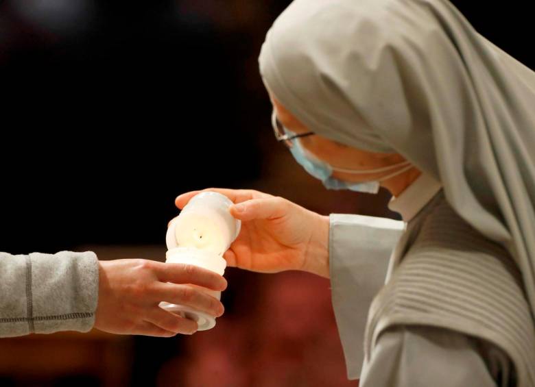 Los fieles comparten un fuego para encender una vela durante la Vigilia Pascual celebrada por el Papa Francisco en una Basílica de San Pedro. Foto: EFE