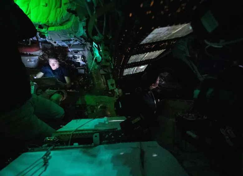 En la fotografía, ña astronauta de la NASA Christina Koch es iluminada por una pantalla dentro de la oscura nave espacial Orion en el tercer día de la misión Artemis II de la agencia. A la derecha del centro de la imagen, se observa de perfil al astronauta de la CSA (Agencia Espacial Canadiense) Jeremy Hansen, mirando por una de las ventanas de la Orion. Las luces están apagadas para evitar reflejos en las ventanas. Foto: NASA