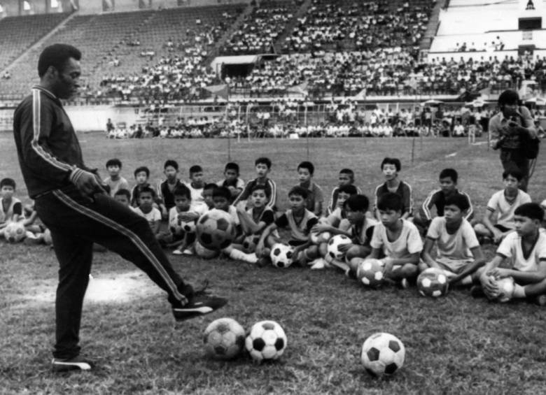 En esta foto tomada el 6 de diciembre de 1974 en Bangkok, se ve al jugador de fútbol brasileño Pelé durante una sesión de entrenamiento con niños como parte de un viaje comercial en Tailandia. Foto: Getty